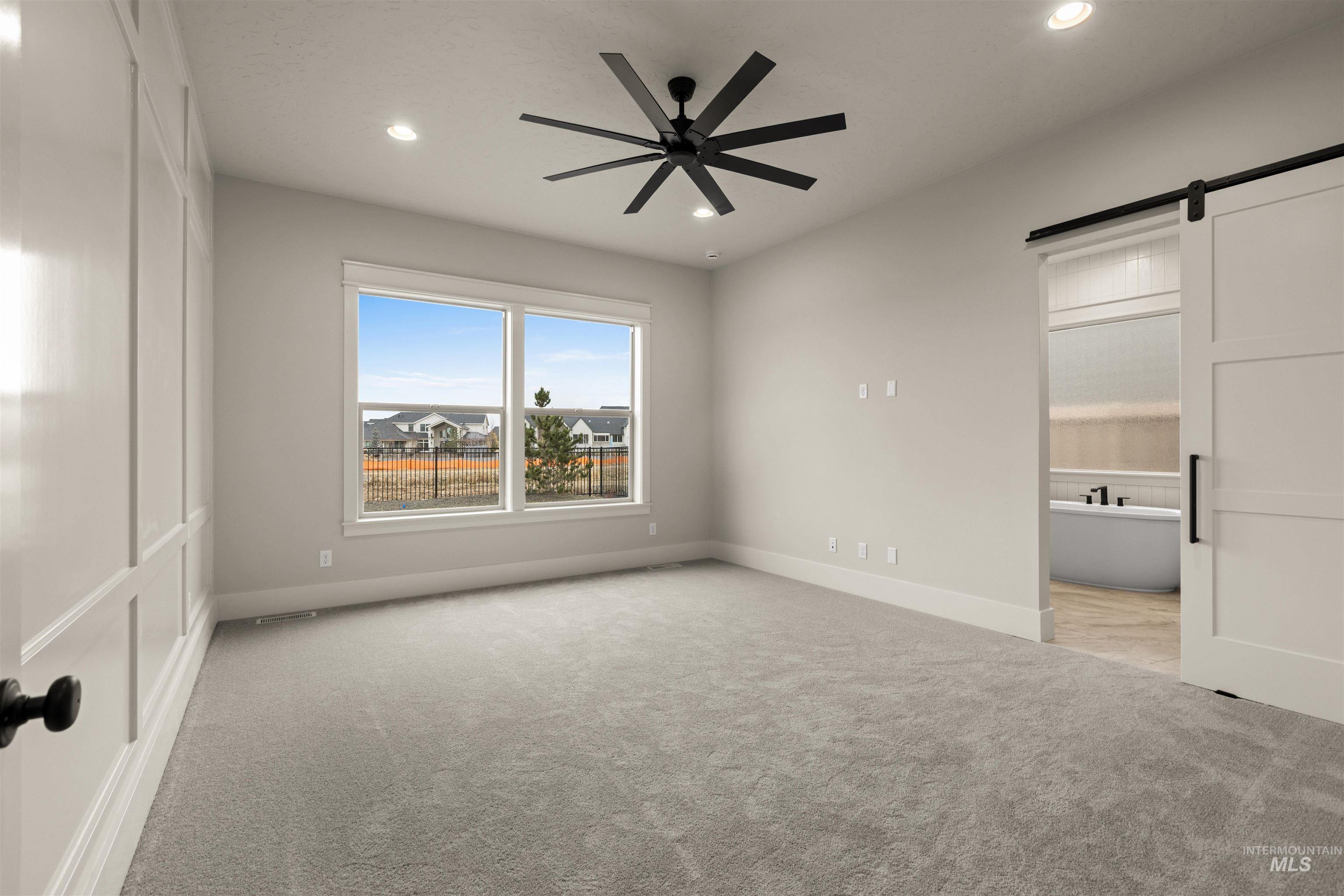 6844 South Messner Way Meridian, ID 83642 - Photo 22 of 49 Unfurnished bedroom featuring a barn door, light colored carpet, ensuite bath, a ceiling fan, and recessed lighting