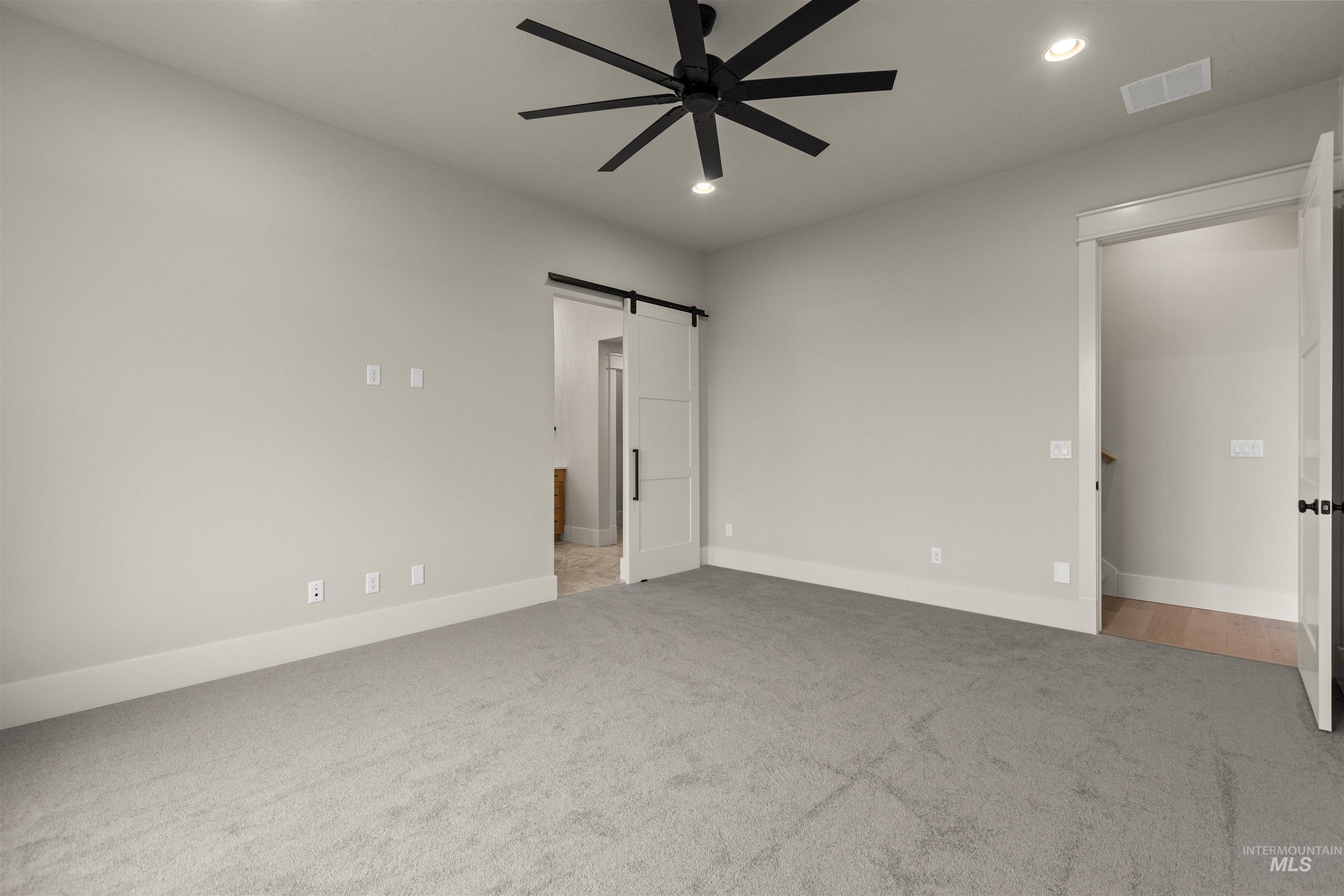 6844 South Messner Way Meridian, ID 83642 - Photo 24 of 49 Unfurnished bedroom featuring a barn door, light carpet, recessed lighting, ceiling fan, and connected bathroom