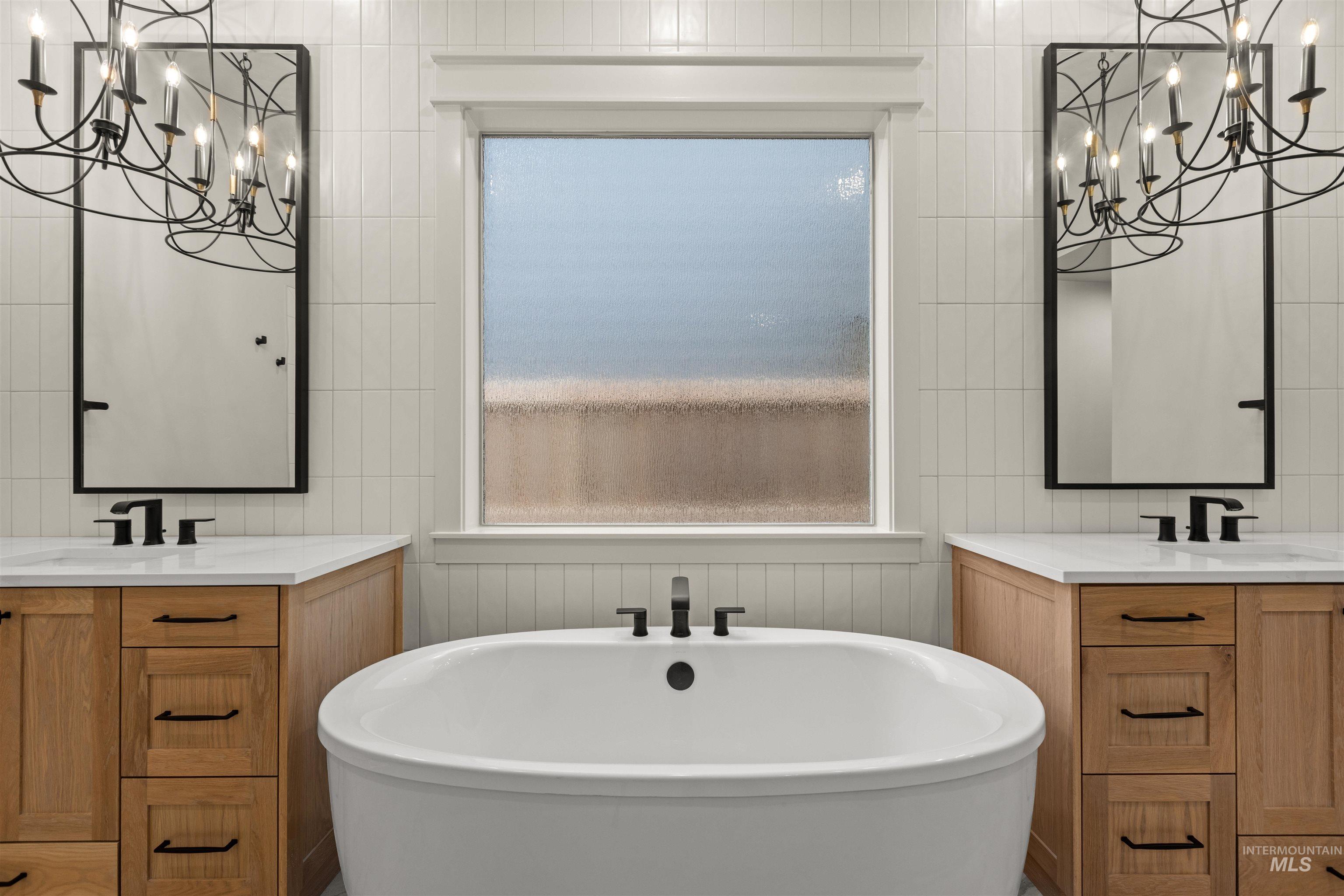 6844 South Messner Way Meridian, ID 83642 - Photo 25 of 49 Bathroom with a chandelier, two vanities, and a freestanding bath