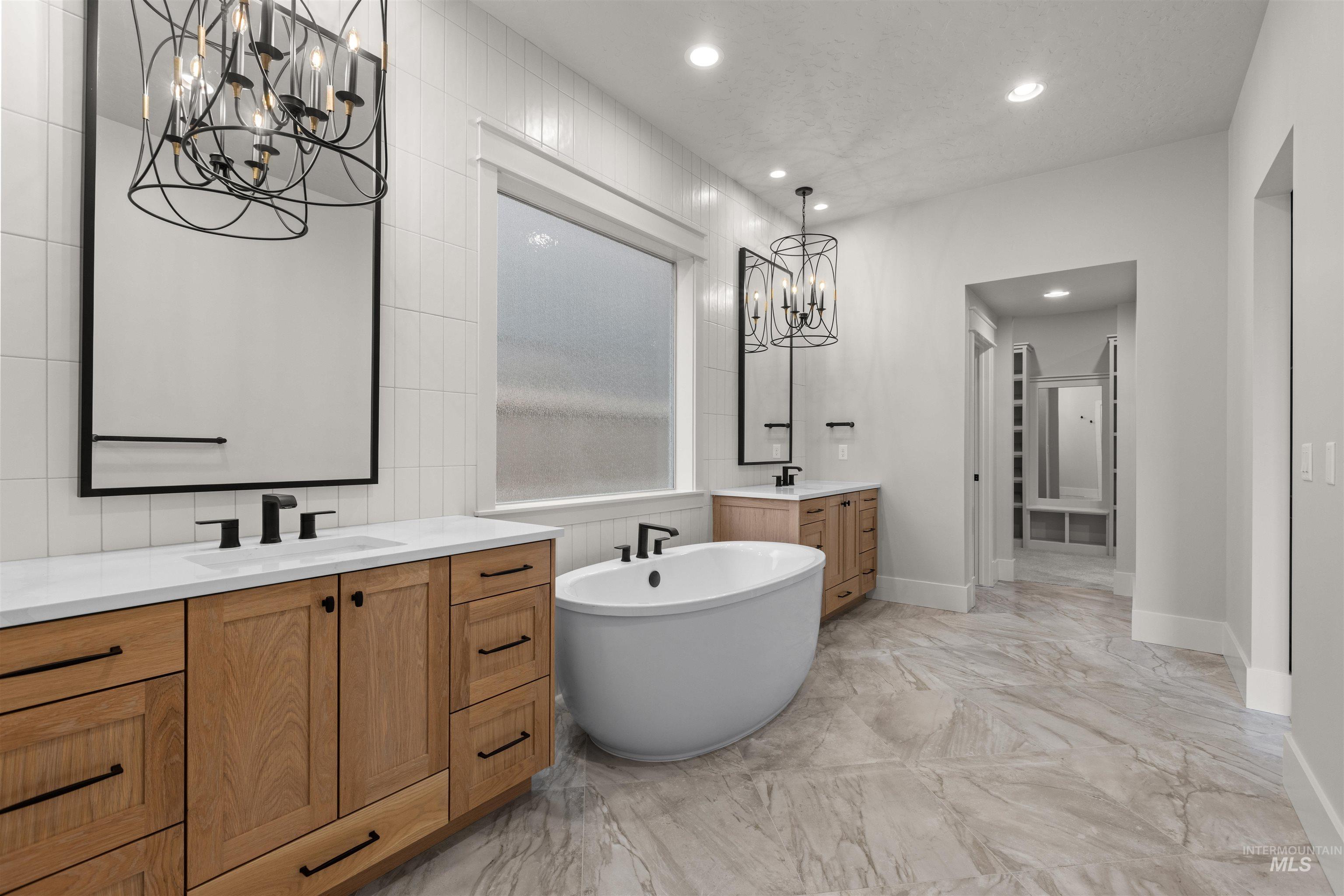 6844 South Messner Way Meridian, ID 83642 - Photo 26 of 49 Bathroom featuring a chandelier, two vanities, recessed lighting, a freestanding tub, and light marble finish floors
