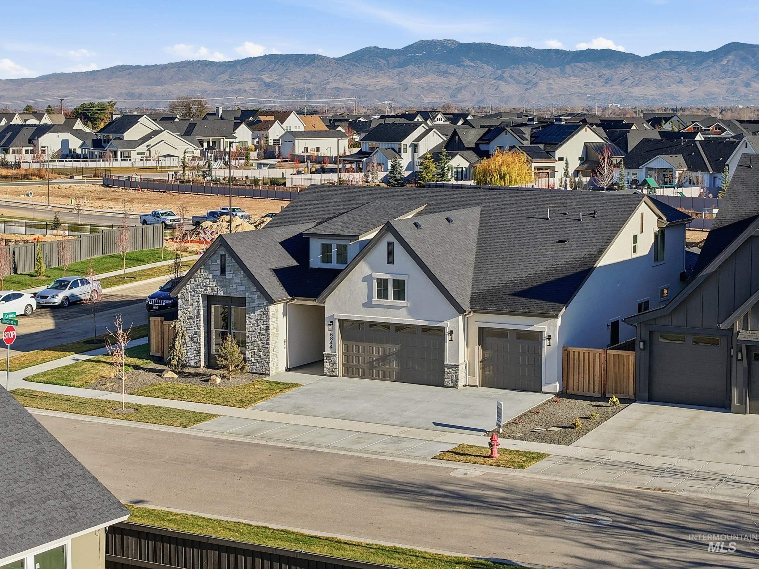 6844 South Messner Way Meridian, ID 83642 - Photo 40 of 49 View of front of property featuring a mountain view, stone siding, a garage, driveway, and a residential view