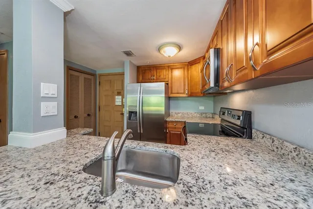 a kitchen with granite countertop a stove a sink and a refrigerator