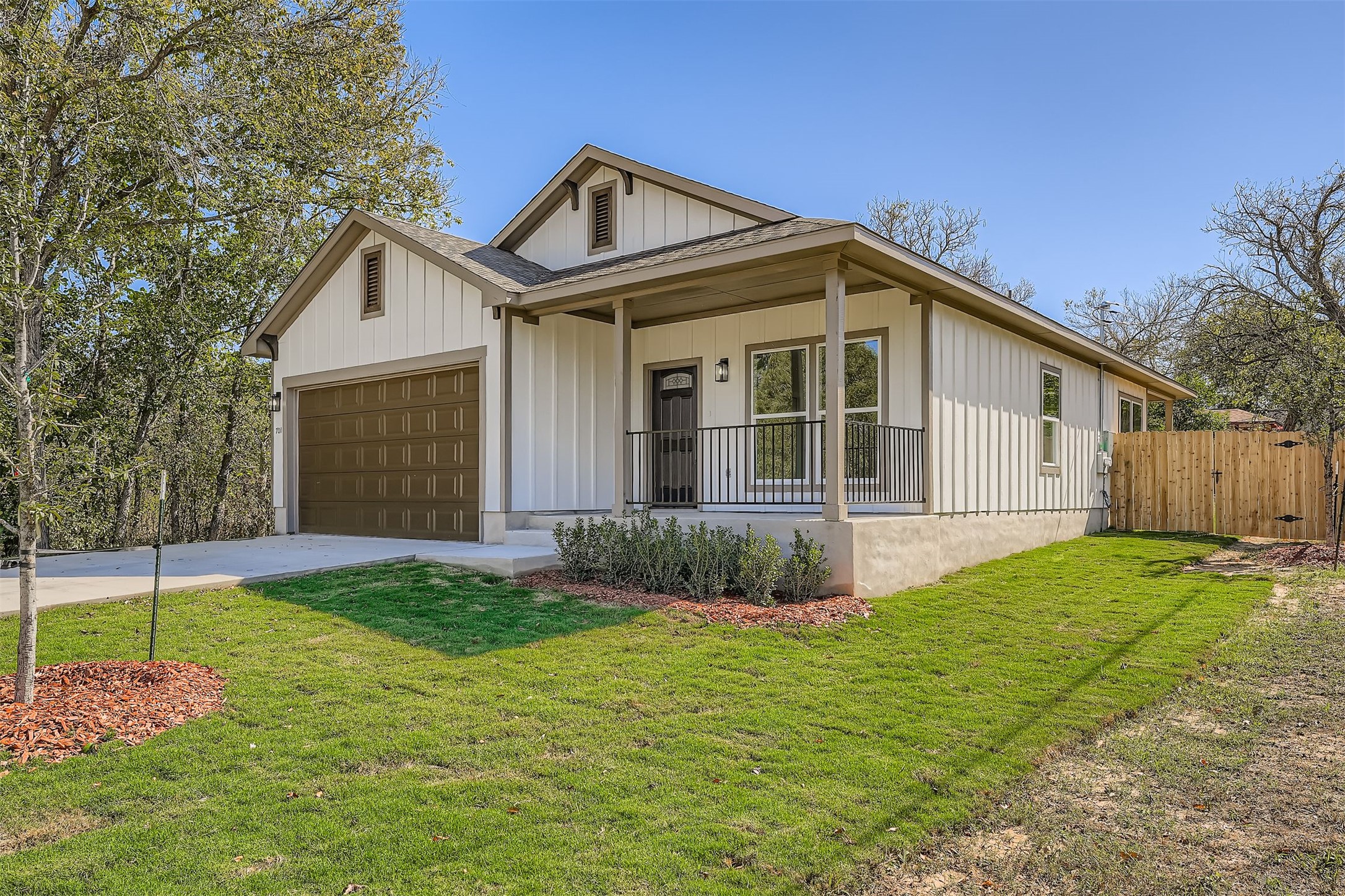 701 East 3rd Street Elgin, TX 78621 - Photo 3 of 35 View of front of property with covered porch, and batten siding, a shingled roof, concrete driveway, and a front lawn
