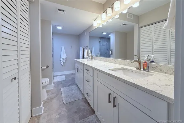 a spacious bathroom with a granite countertop sink a toilet a mirror and shower