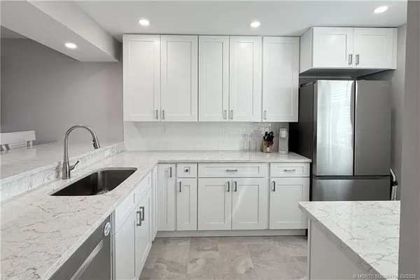 a kitchen with granite countertop a sink stove and refrigerator