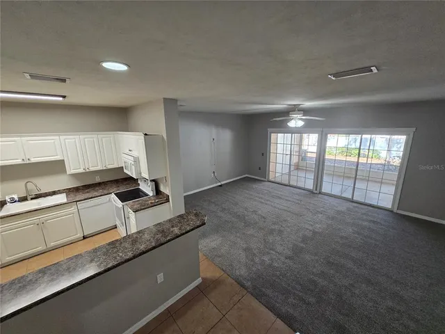 a large white kitchen with granite countertop a sink and a stove