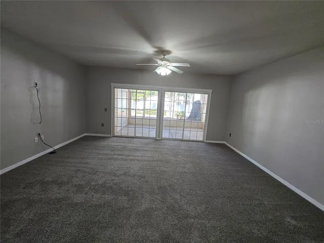 an empty room with chandelier fan and windows