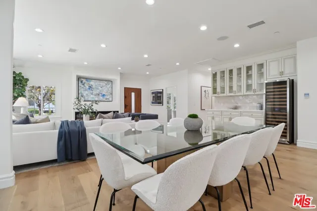 a dinning room with stainless steel appliances kitchen island granite countertop a dining table chairs and a refrigerator
