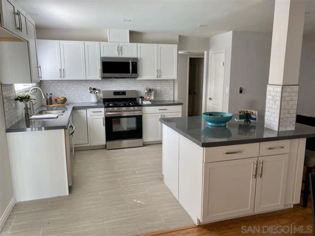 a kitchen with granite countertop a stove top oven sink and cabinets