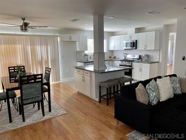 a kitchen with stainless steel appliances granite countertop a table chairs sink and cabinets