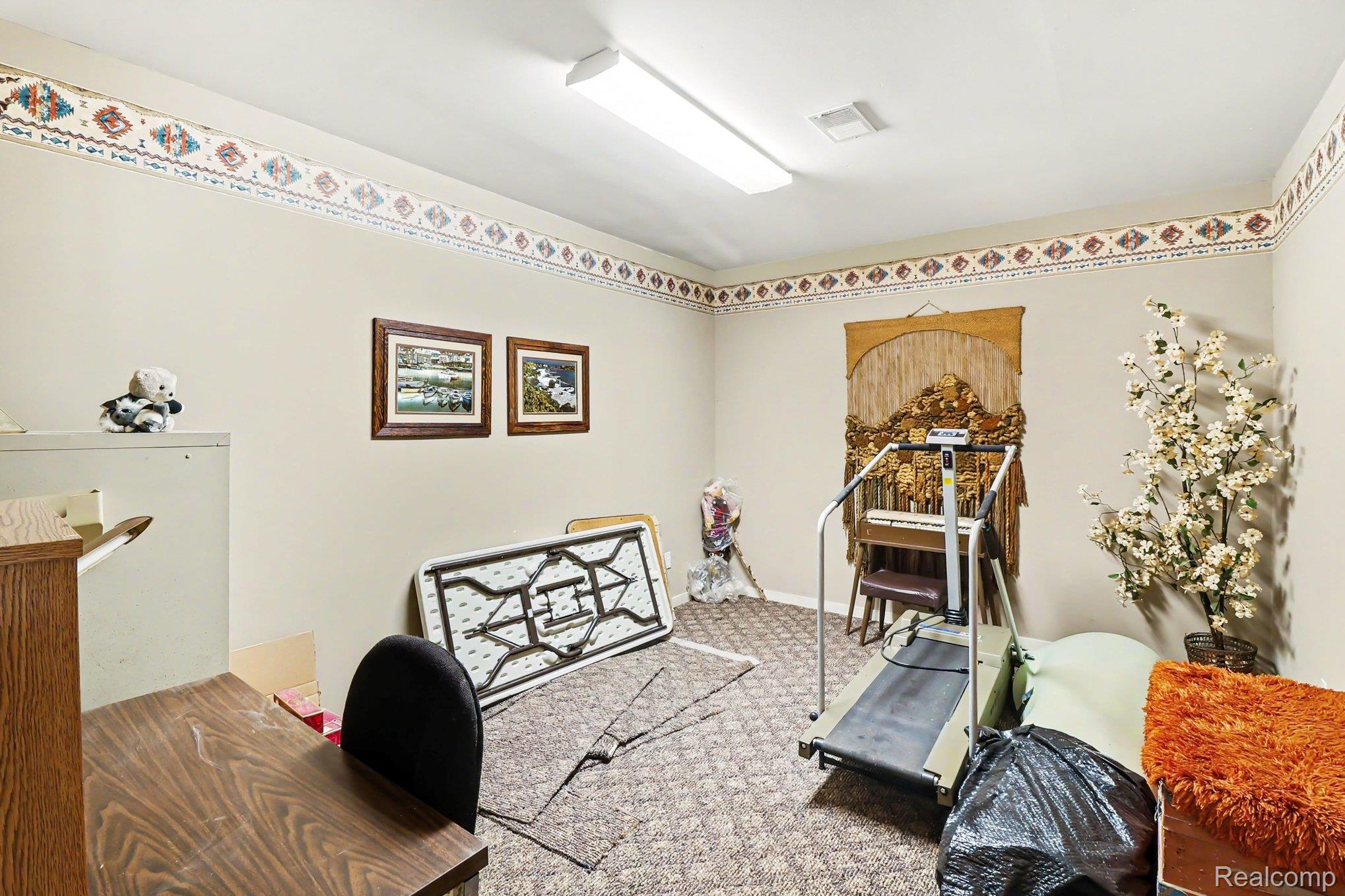 18501 Taylor Lake Road Holly, MI 48442 - Photo 23 of 35 Carpeted room with a decorative wallpaper border and a fluorescent ceiling light fixture
