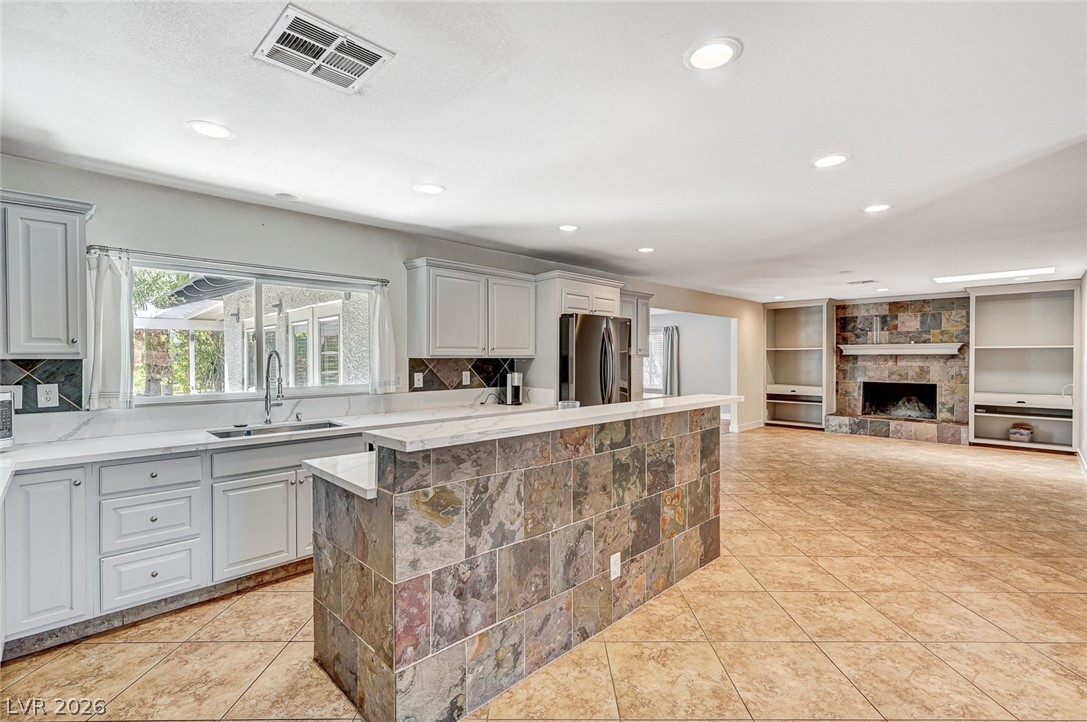 4153 Woodcrest Road Las Vegas, NV 89121 - Photo 12 of 58 A spacious, naturally illuminated kitchen and living area feature a tile-clad island and a stately fireplace.