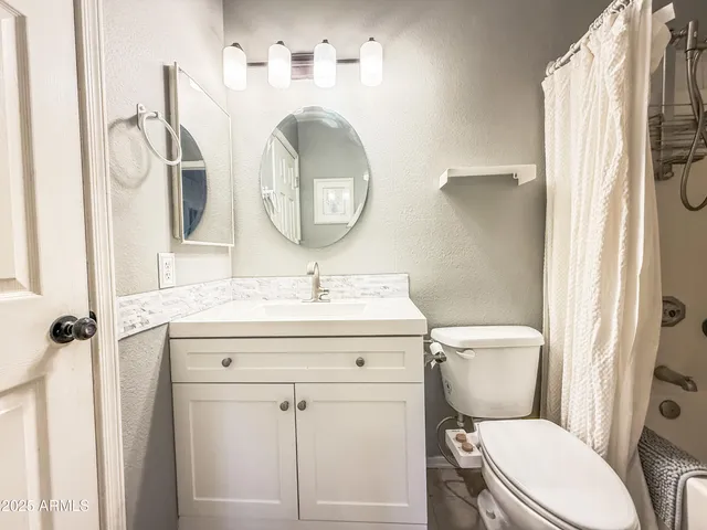 a bathroom with a granite countertop toilet sink and mirror
