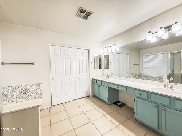 a large white kitchen with a sink and dishwasher with a large mirror
