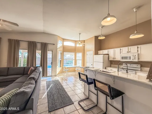 a large living room with stainless steel appliances granite countertop furniture a couch and a large window