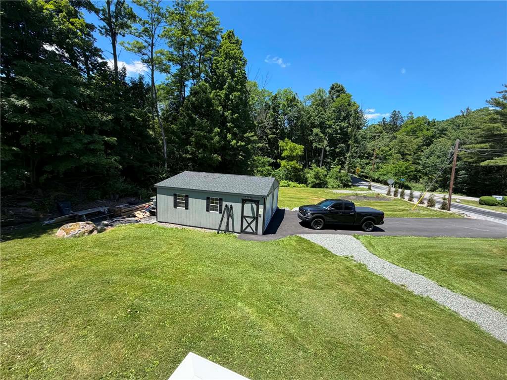 164 Sand Spring Road Cresco, PA 18326 - Photo 26 of 60 A quaint storage shed and lush green yard provide practical outdoor space on a sun-drenched day.