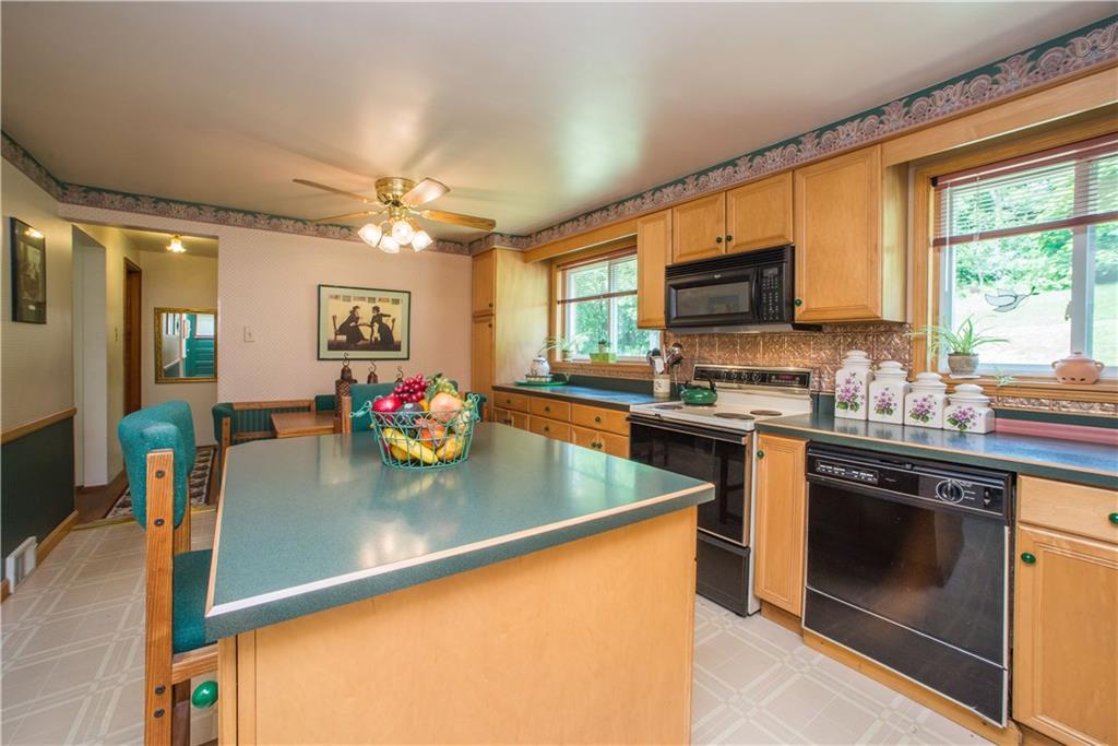 1313 McCully Road Pittsburgh, PA 15234 - Photo 7 of 25 The sunny kitchen gets its natural light from two windows overlooking the rear of the property. The island offers casual seating and storage.
