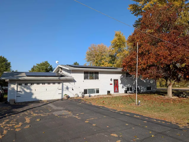 a view of a white house with a big yard and large trees
