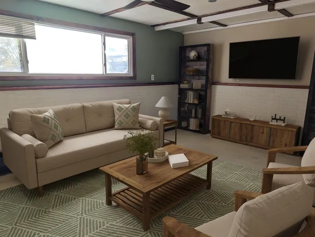 a living room with furniture a flat screen tv and a window