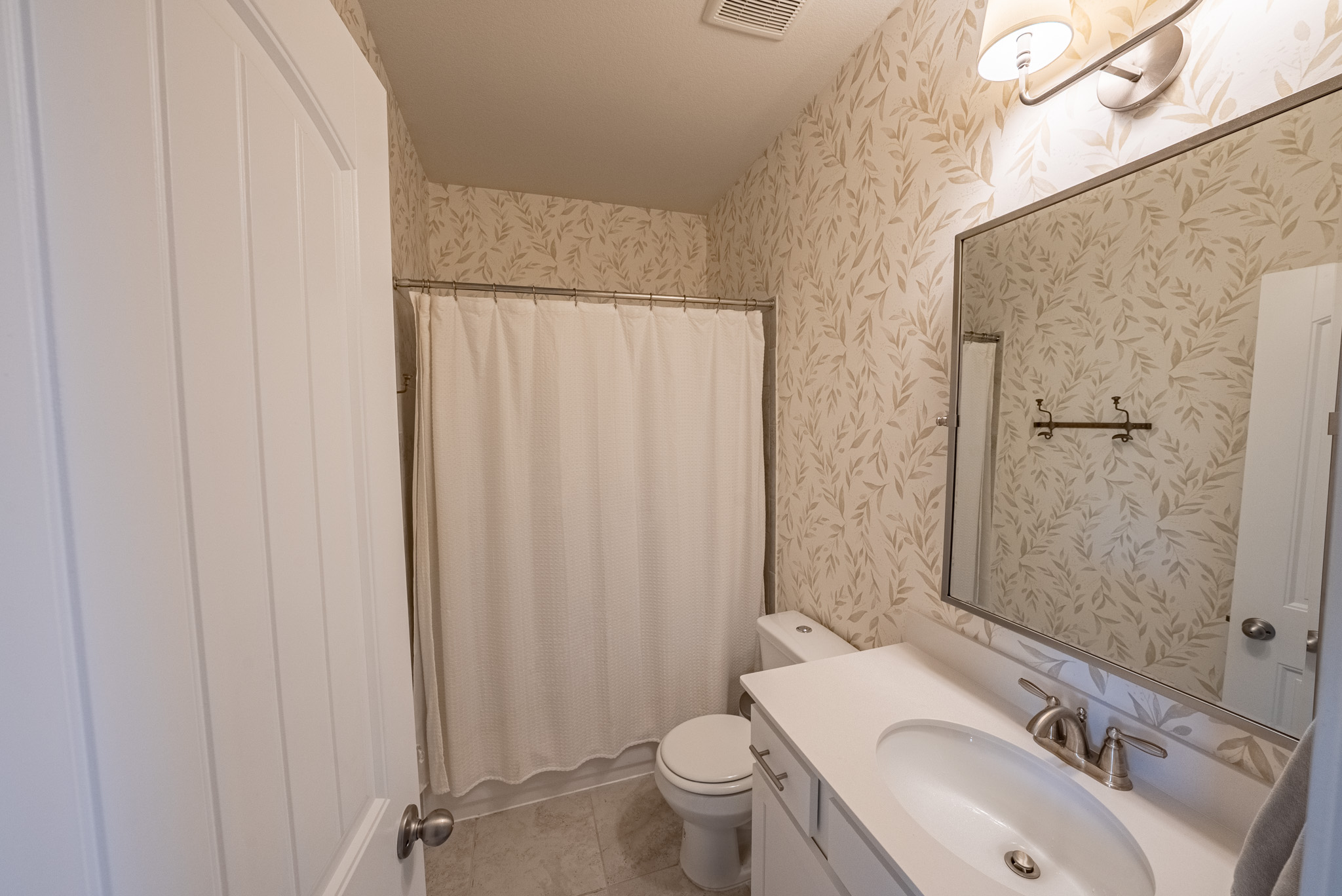 2508 Hat Bender Loop Round Rock, TX 78664 - Photo 18 of 22 Bathroom featuring a vanity with an integrated sink and brushed nickel faucet, a frameless mirror, and botanical-patterned wallpaper