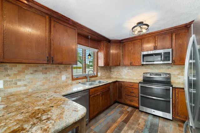 a kitchen with granite countertop wooden cabinets stainless steel appliances and a sink