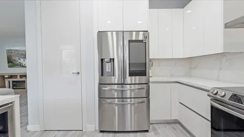 a kitchen with stainless steel appliances wooden floor and a refrigerator