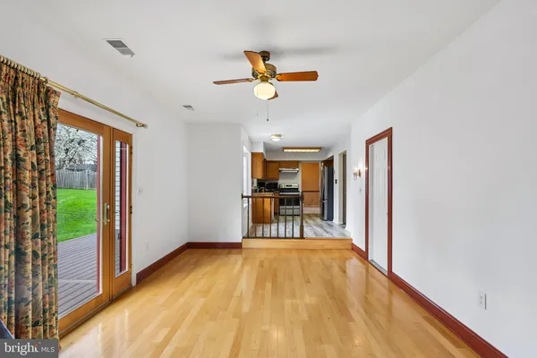 a view of a livingroom with wooden floor a ceiling fan and windows