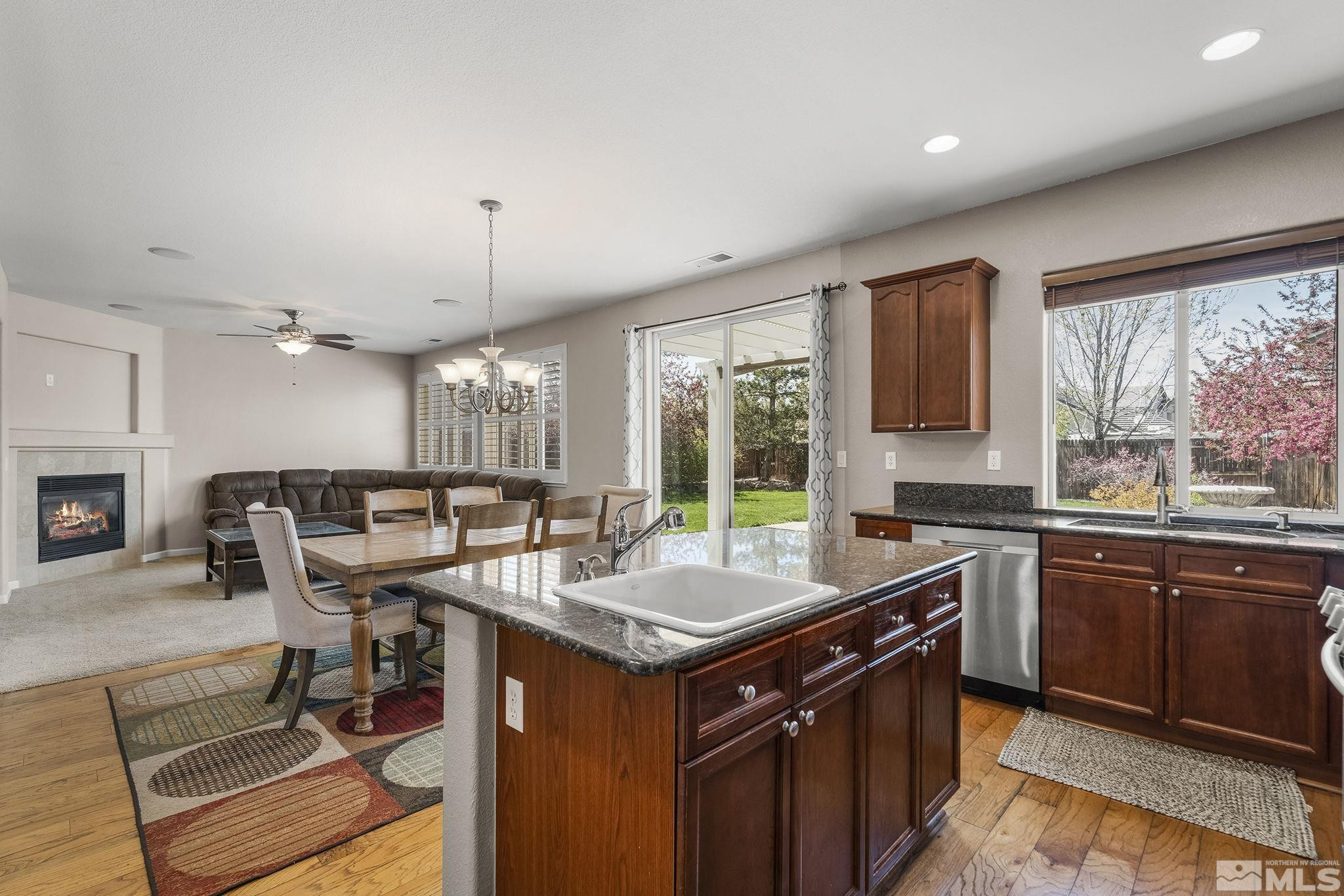10537 Fort Morgan Way Reno, NV 89521 - Photo 13 of 30 a kitchen with a stove a sink dishwasher a dining table and chairs with wooden floor