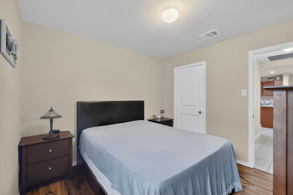 1409 Slate Street Princeton, TX 75407 - Photo 26 of 36 Bedroom featuring wood-finish flooring, a neutral wall color, and a white paneled door