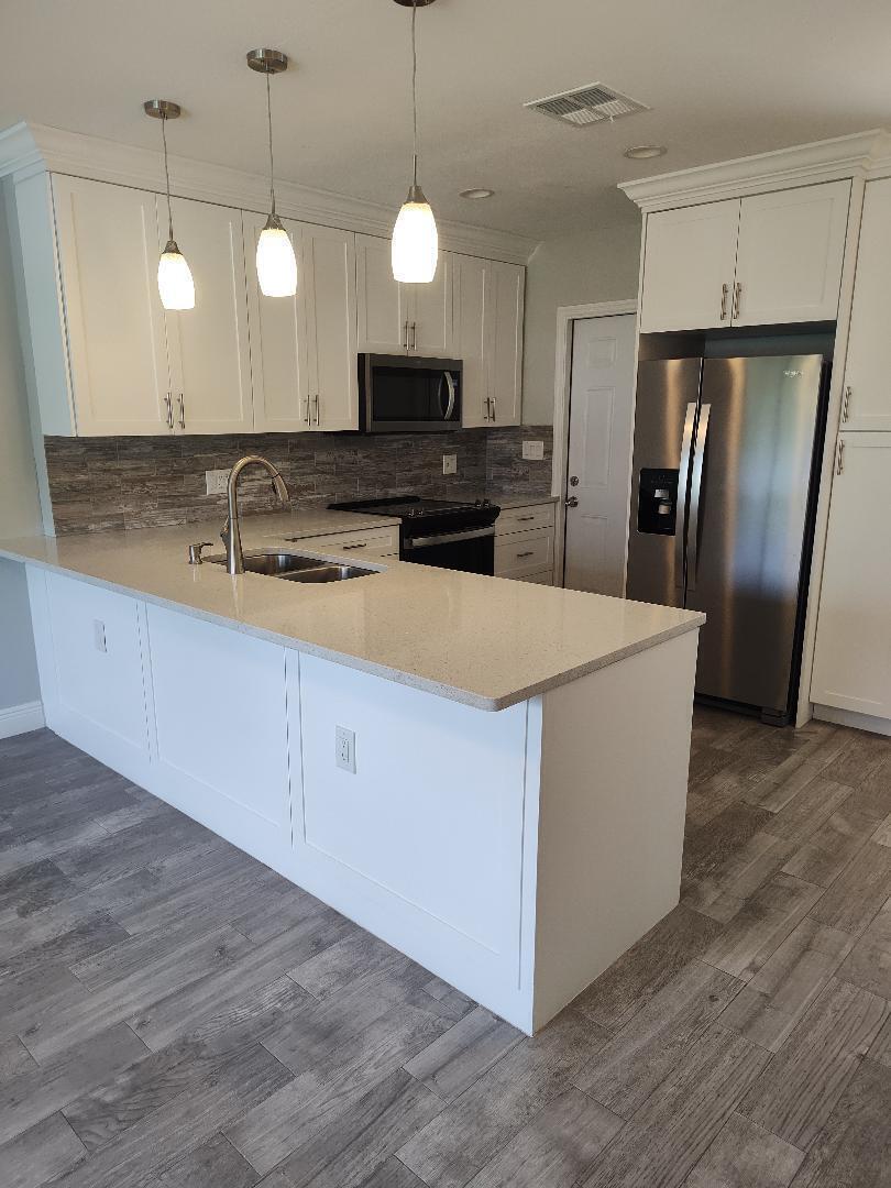 2248 Northeast 37th Street Lighthouse Point, FL 33064 - Photo 4 of 19 a large kitchen with stainless steel appliances kitchen island a large counter top and wooden floors
