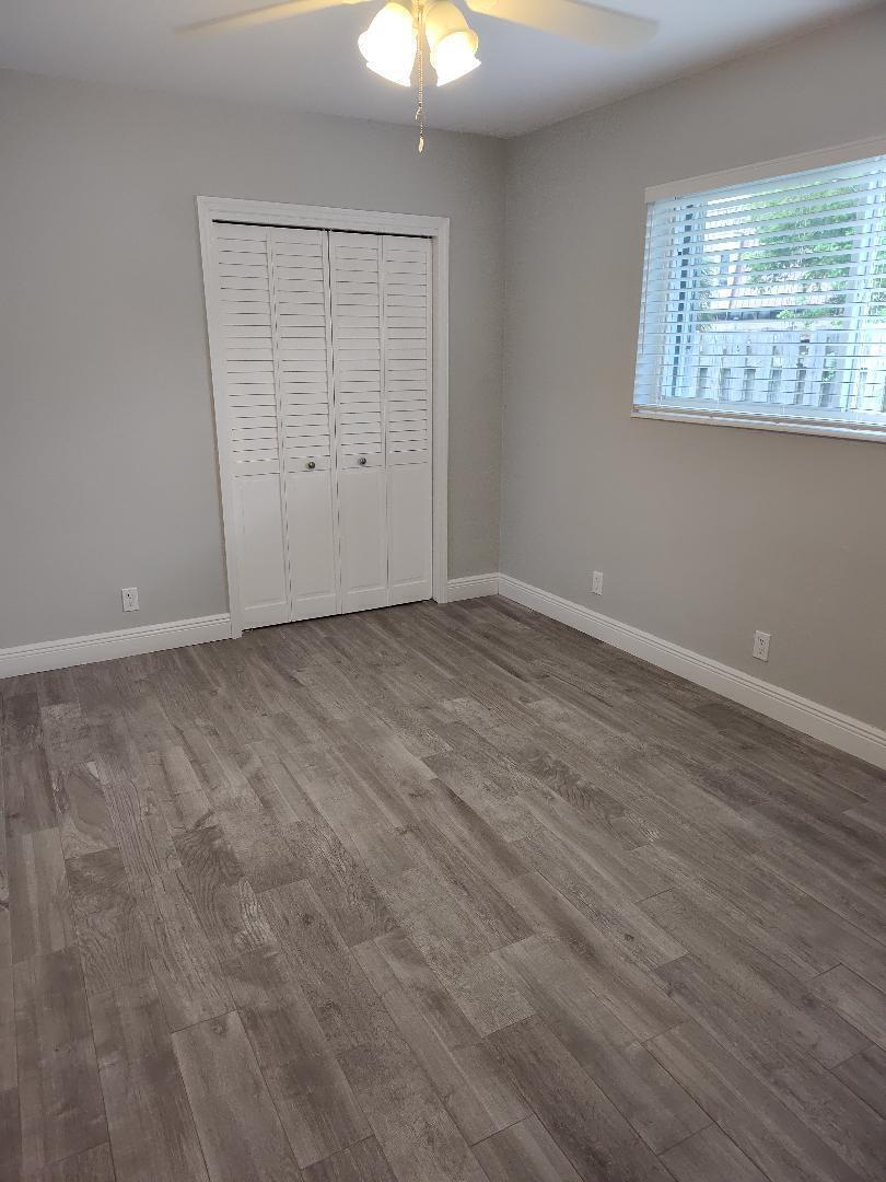 2248 Northeast 37th Street Lighthouse Point, FL 33064 - Photo 9 of 19 an empty room with wooden floor chandelier fan and windows