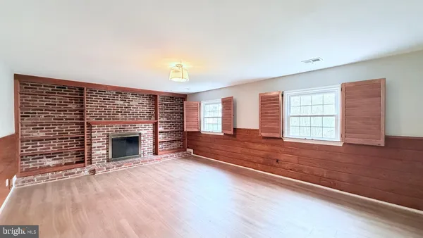 a view of empty room with wooden floor and fireplace