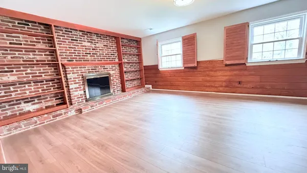 a view of empty room with wooden floor and fireplace