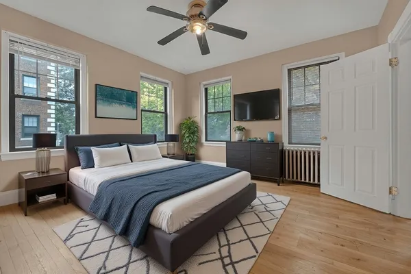 a bedroom with a bed a chandelier and a flat screen tv