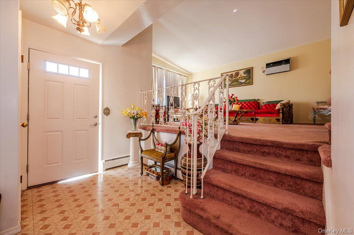 10 Meadow Road Inwood, NY 11096 - Photo 3 of 22 Foyer entrance featuring a baseboard heating unit, lofted ceiling, a chandelier, stairs, and light floors