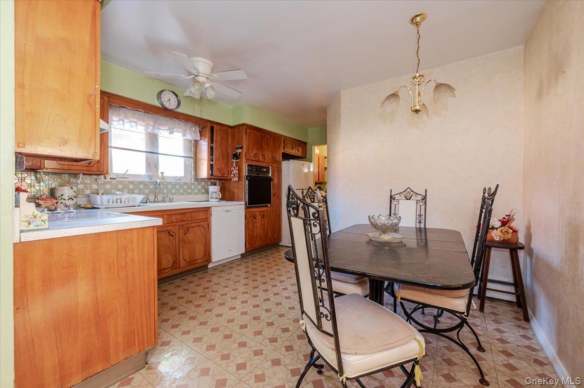 10 Meadow Road Inwood, NY 11096 - Photo 8 of 22 Kitchen featuring light countertops, decorative backsplash, brown cabinets, decorative light fixtures, and white appliances