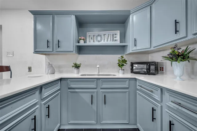 a kitchen with white cabinets and a potted plant