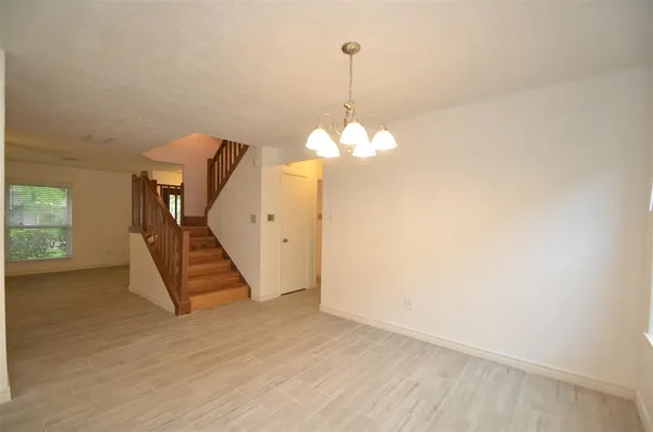 a view of an empty room with wooden floor staircase and a kitchen