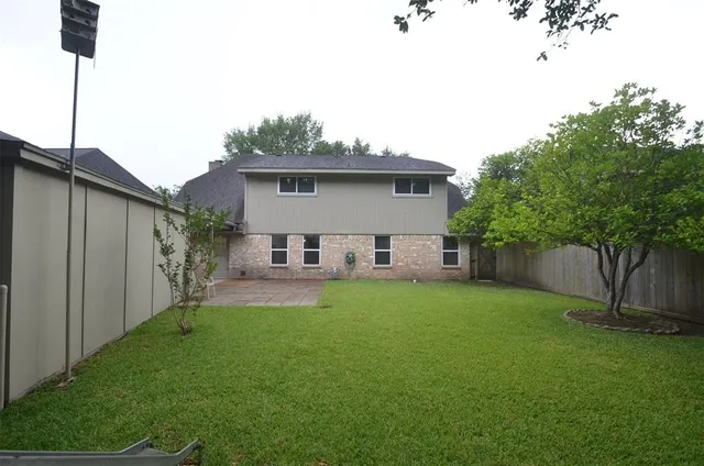a view of a house with a backyard and a tree