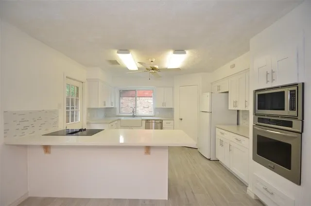 a large kitchen with kitchen island a large counter space stainless steel appliances and cabinets