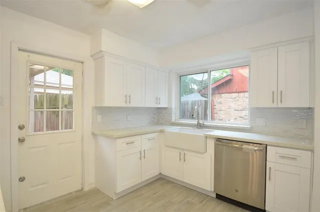 a kitchen with white cabinets and window