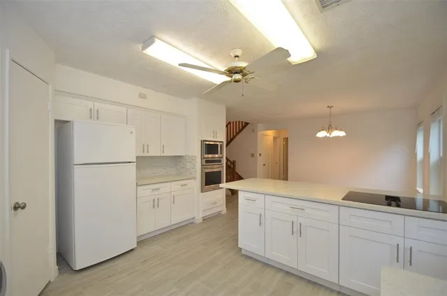 a kitchen with white cabinets and refrigerator