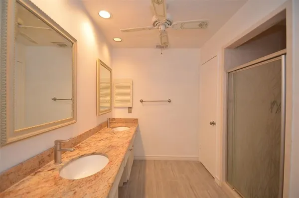 a bathroom with a granite countertop sink a mirror and shower