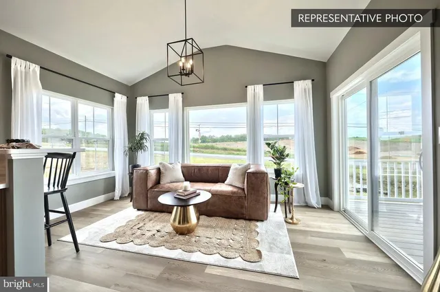 a living room with furniture large windows and wooden floor