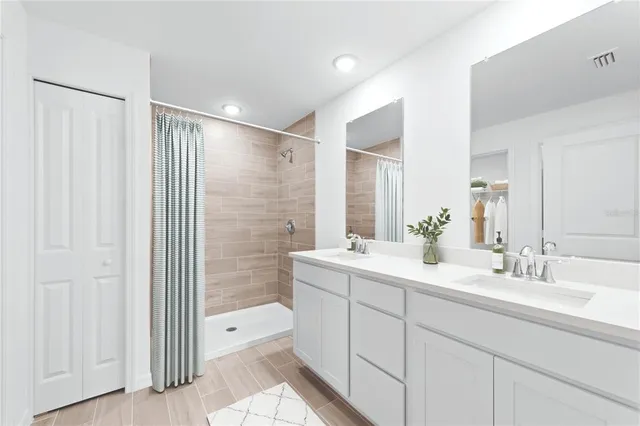 a bathroom with a double vanity sink a large mirror and shower