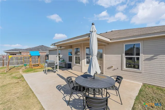 a patio with a table and chairs and potted plants