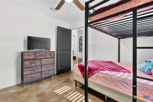 a bedroom with a bed and a flat tv screen on dresser