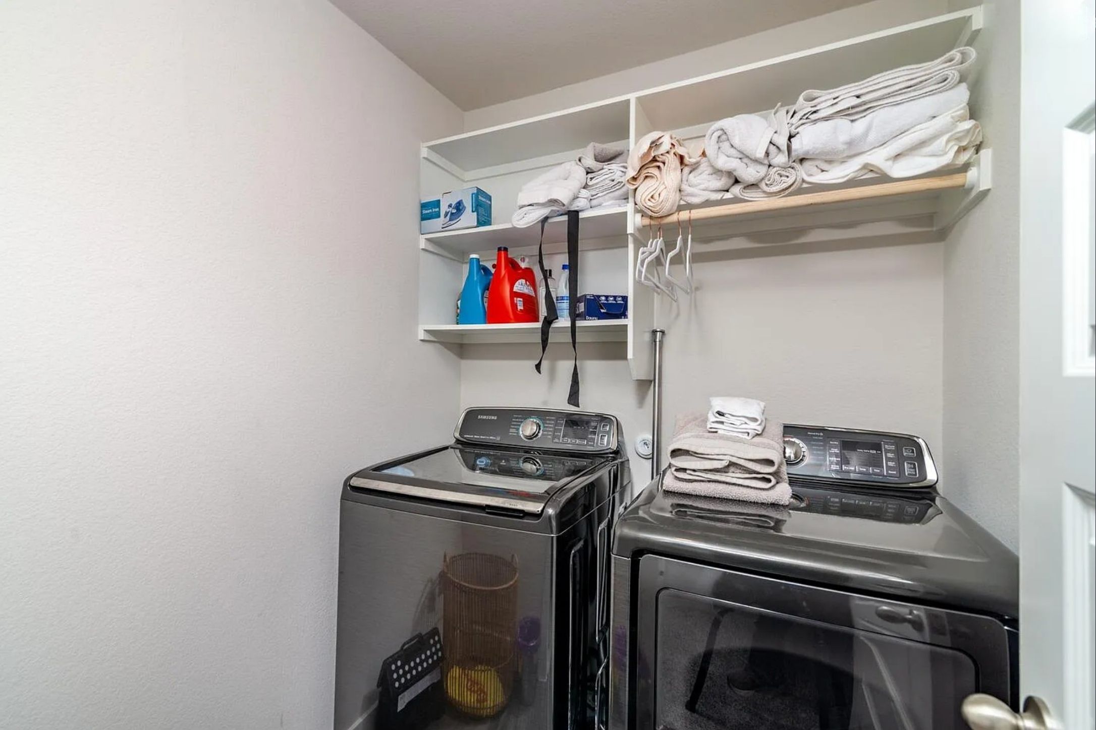 7501 Travertine Spring Drive Austin, TX 78744 - Photo 25 of 28 Dedicated laundry area featuring a washer and dryer, open shelving, and a hanging rod for convenience