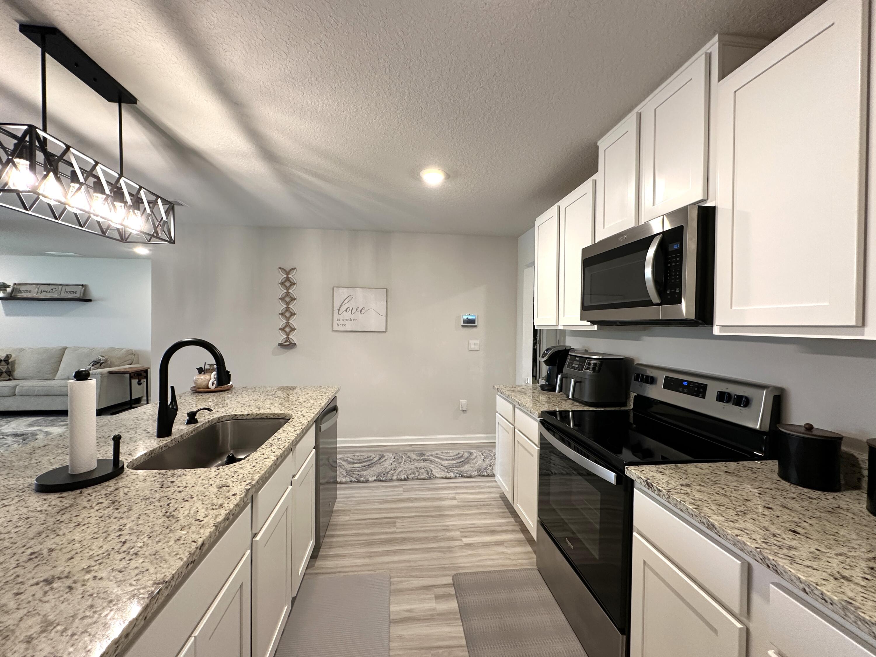 828 Otto Loop Crestview, FL 32539 - Photo 9 of 30 a kitchen with kitchen island granite countertop a sink stainless steel appliances and cabinets