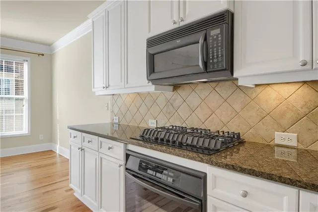 a kitchen with granite countertop white cabinets and stainless steel appliances